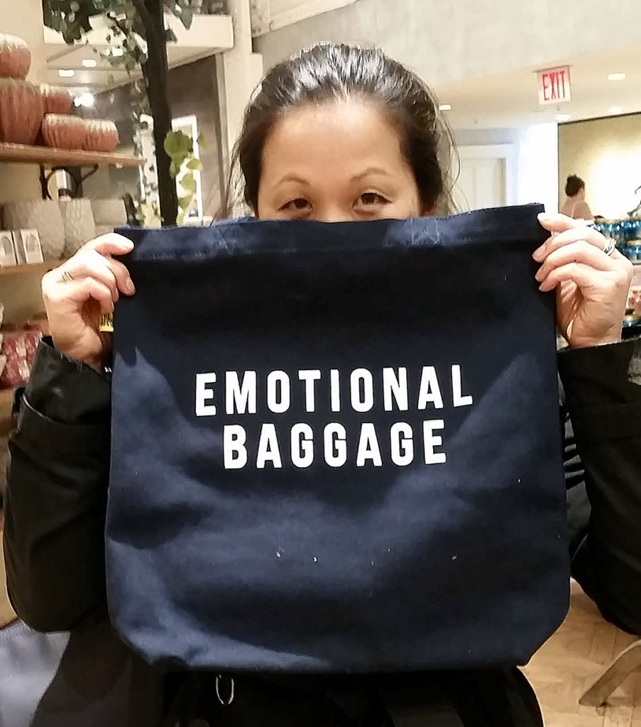 Foto av artikkelforfatteren som holder opp en pose med den engelskspråklige påskriften Emotional Baggage.