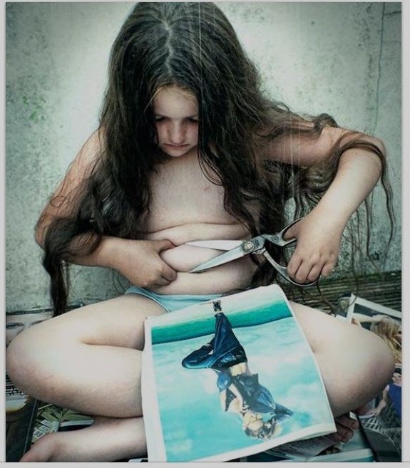 Kunstfoto tatt av Meg Gaiger, som viser et barn som prøver å klippe i magefettet med saks.