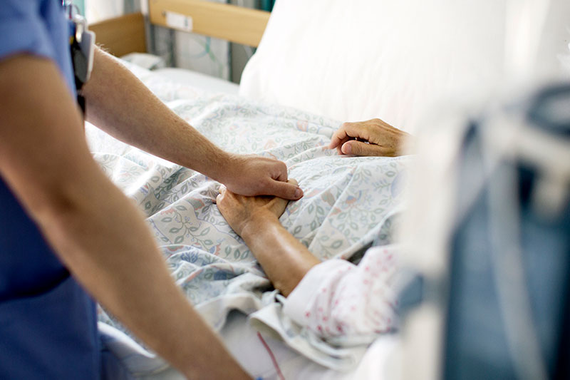 Sykepleier holder hånd til eldre